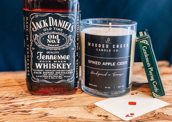 Spiked Apple Cider displayed with whiskey and apple cider candle